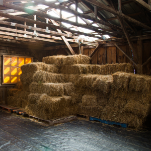bales of hay stacked and stored in barn - one of our Top Tips for Storing Hay in Hot Weather is to master the art of stacking!